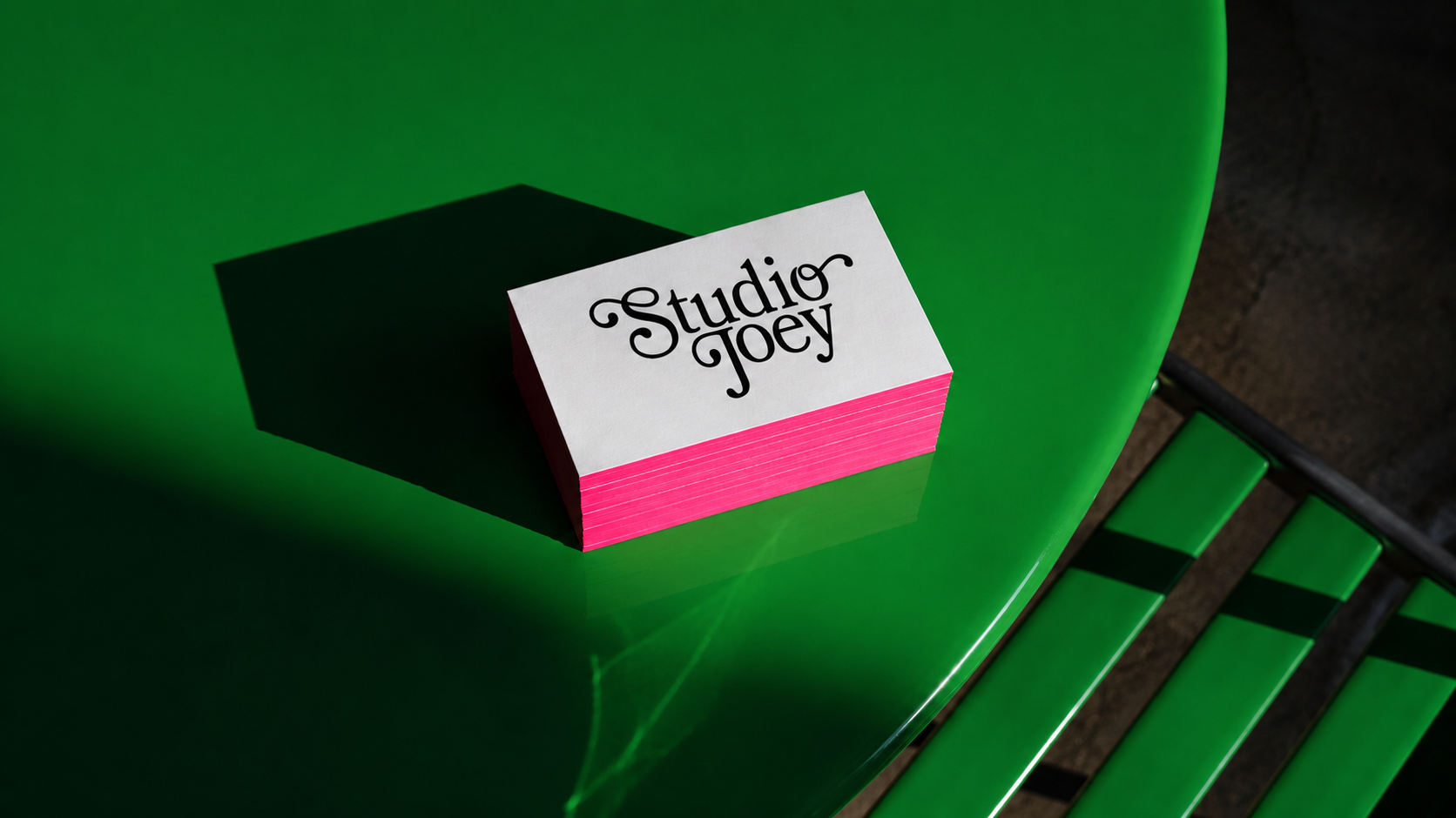 Studio Joey business cards with pink edges on green table